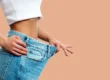 Close-up of a woman showing loose jeans after significant weight loss, representing success from a Weight Loss Program in South Ogden UT.