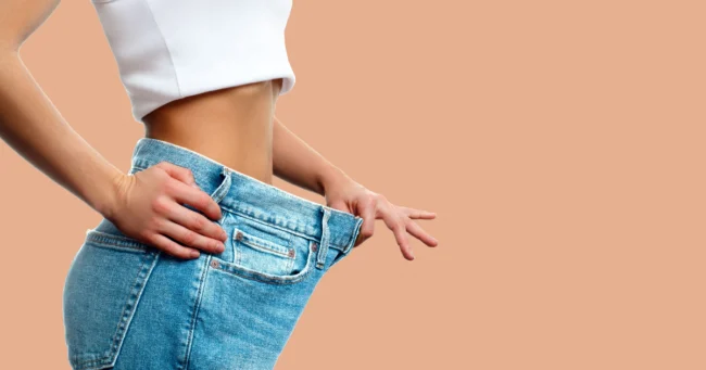 Close-up of a woman showing loose jeans after significant weight loss, representing success from a Weight Loss Program in South Ogden UT.