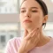 A woman gently touching her neck, representing thyroid function concerns in South Ogden, UT