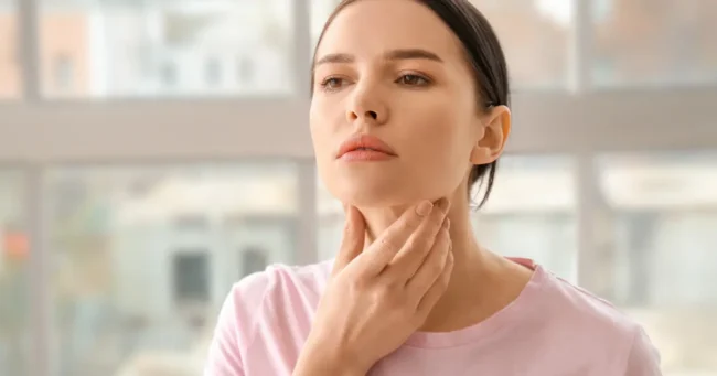 A woman gently touching her neck, representing thyroid function concerns in South Ogden, UT