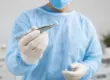 Healthcare provider in a clinical setting holding a hormone pellet with sterile tweezers before a hormone pellet therapy procedure.