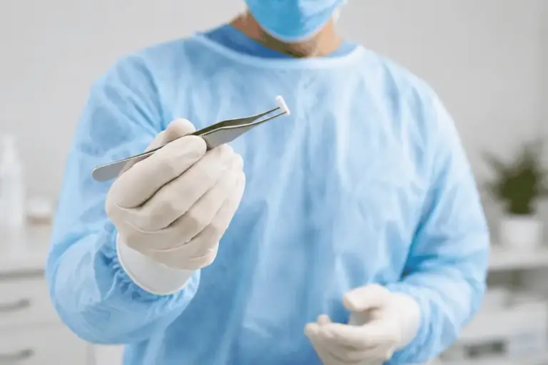 hormone-pellet-therapy-medical-provider-holding-pellet Healthcare provider in a clinical setting holding a hormone pellet with sterile tweezers before a hormone pellet therapy procedure.