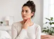 Woman experiencing low thyroid symptoms and touching her throat